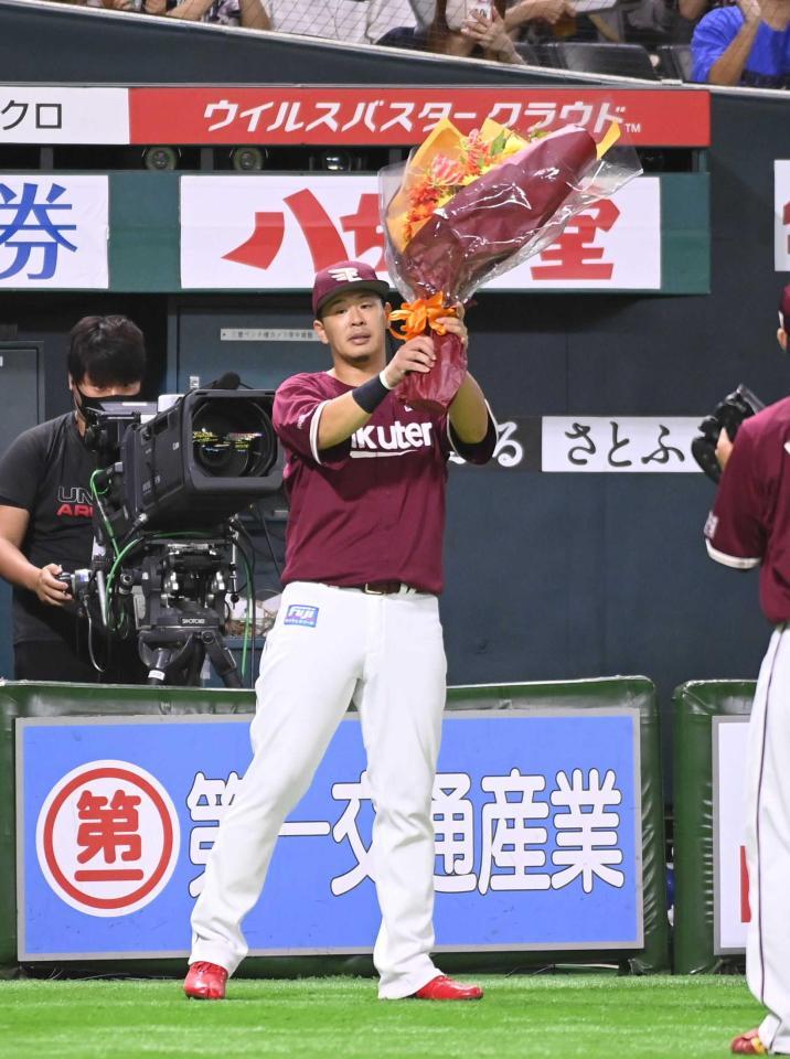 　１０００試合連続出場を達成し、花束を手にする浅村