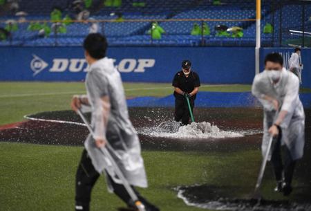 豪雨でできたブルペンの水たまりをトンボで除去する球場スタッフ＝神宮球場（撮影・開出牧）
