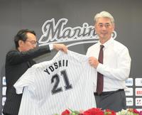 　河合オーナー代行兼社長（左）からユニホームを着せてもらう吉井新監督（撮影・堀内翔）