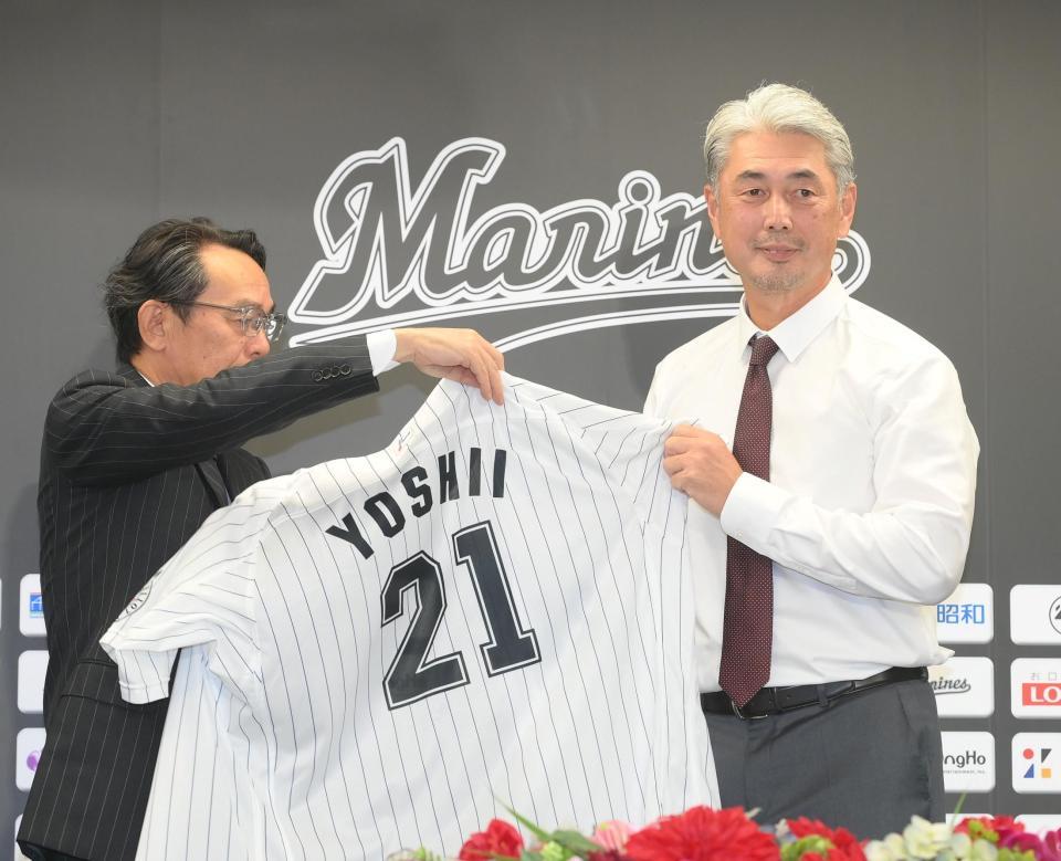 　河合オーナー代行兼社長（左）からユニホームを着せてもらう吉井新監督（撮影・堀内翔）