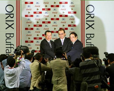 　岡田新監督の就任会見でポーズをとる西名球団社長（左）＝２００９年１０月１４日、京セラドーム