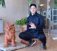 　シーサーの横で笑顔を見せる松尾（撮影・佐藤厚）