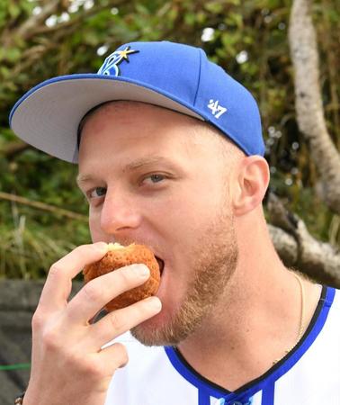 　サーターアンダギーにかぶりつくアンバギー（撮影・佐藤厚）