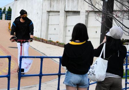 　電動キックボードで颯爽と球場入りする新庄監督（左）