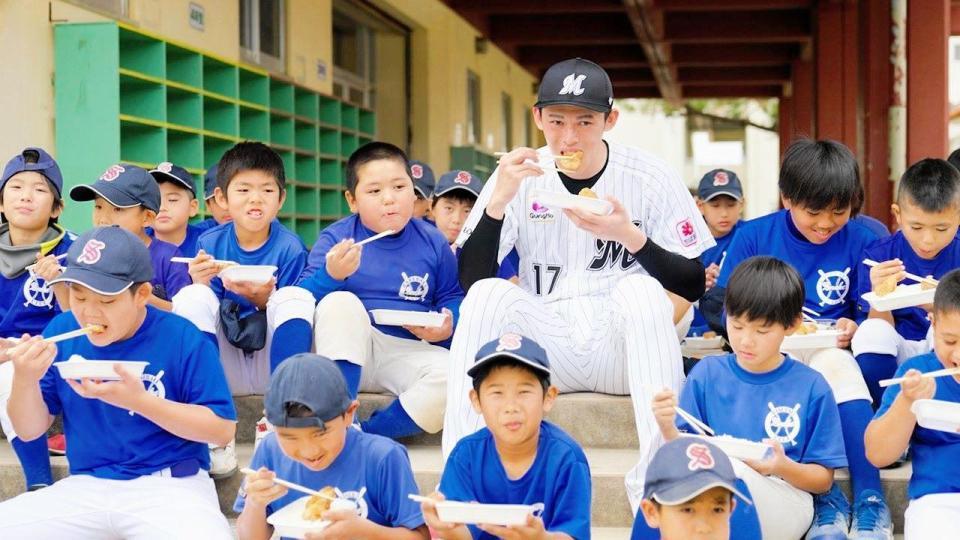 　ＣＭ撮影で子どもたちと「ほっともっと」のから揚げ弁当を食べる佐々木朗（球団提供）