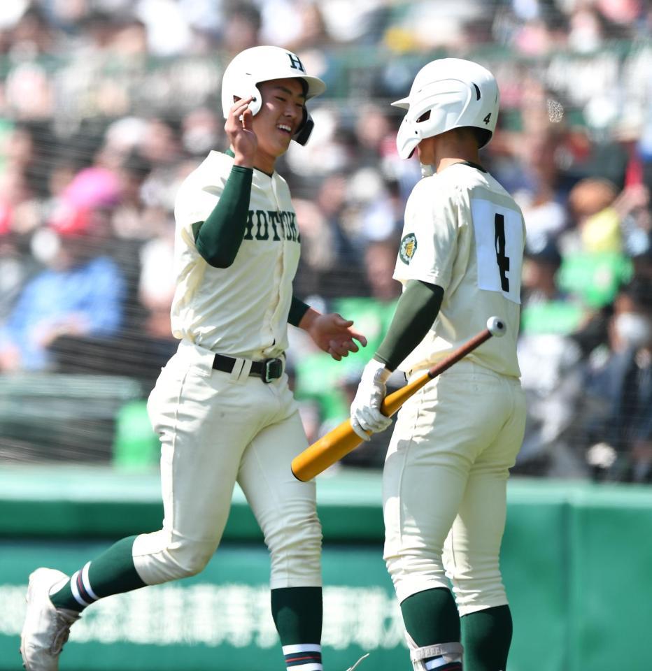 　４回、ボークで三塁から先制のホームを踏み、林純司（右）とタッチを交わす報徳学園・堀柊那（撮影・開出牧）