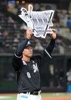 　通算千試合出場を達成し、ボードを掲げる中村奨