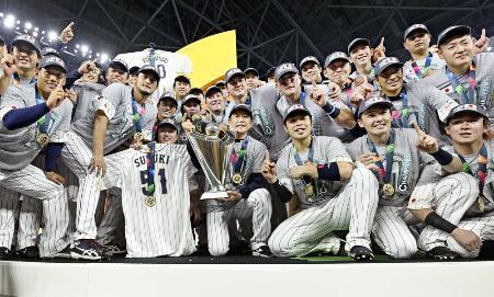 　ＷＢＣを制し、トロフィーを手にした栗山監督を中心に記念写真に納まる日本代表＝３月２１日、マイアミ（共同）