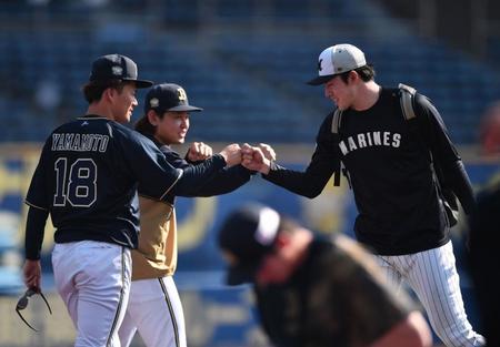 　１８日、試合前の練習を終えあいさつに来た佐々木朗（右）とグータッチを交わす山本（手前）。左後方は宮城（撮影・開出牧）