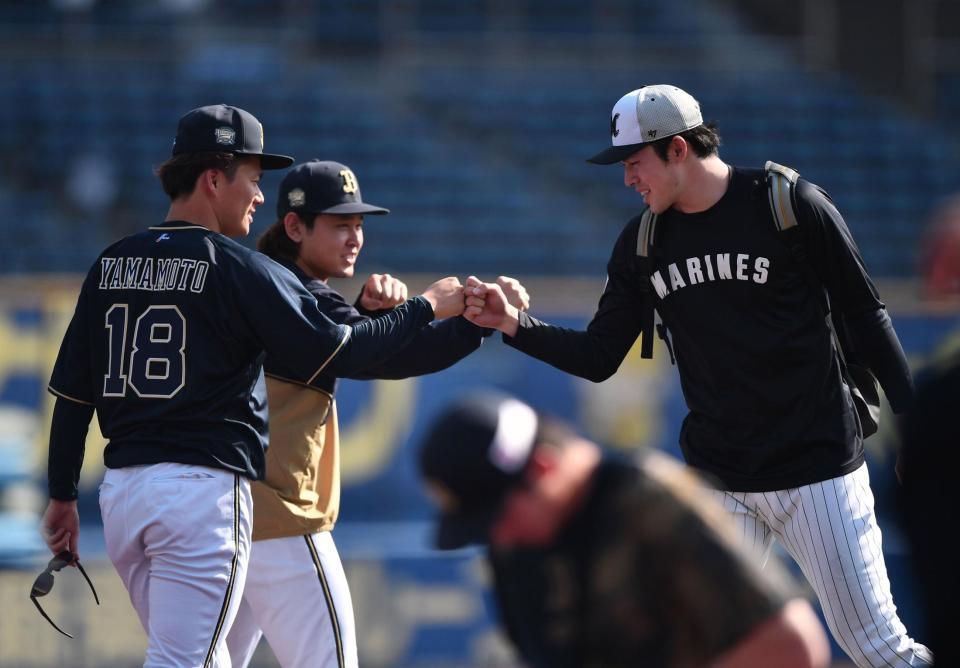 　１８日、試合前の練習を終えあいさつに来た佐々木朗（右）とグータッチを交わす山本（手前）。左後方は宮城（撮影・開出牧）