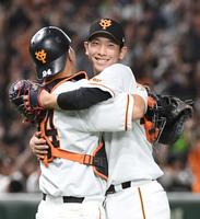 　熱投１４９球の完投で１０勝目を挙げ、大城卓（左）と抱き合う戸郷（撮影・佐藤厚）