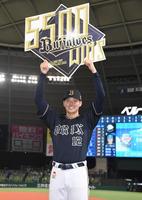 　球団通算５５００勝の記念ボードを笑顔で掲げる山下（撮影・棚橋慶太）