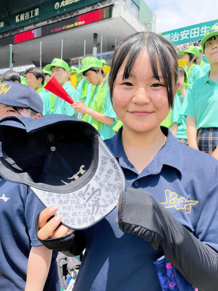 　３年生部員全員の名前が書かれた帽子を手に笑顔を見せる上田西・丸山華那マネジャー