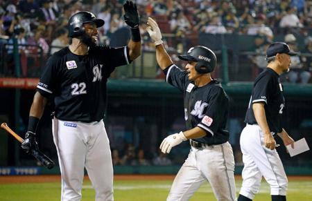 　９回、勝ち越し打を放ち、ポランコ（左）とタッチを交わす荻野。右は吉井監督