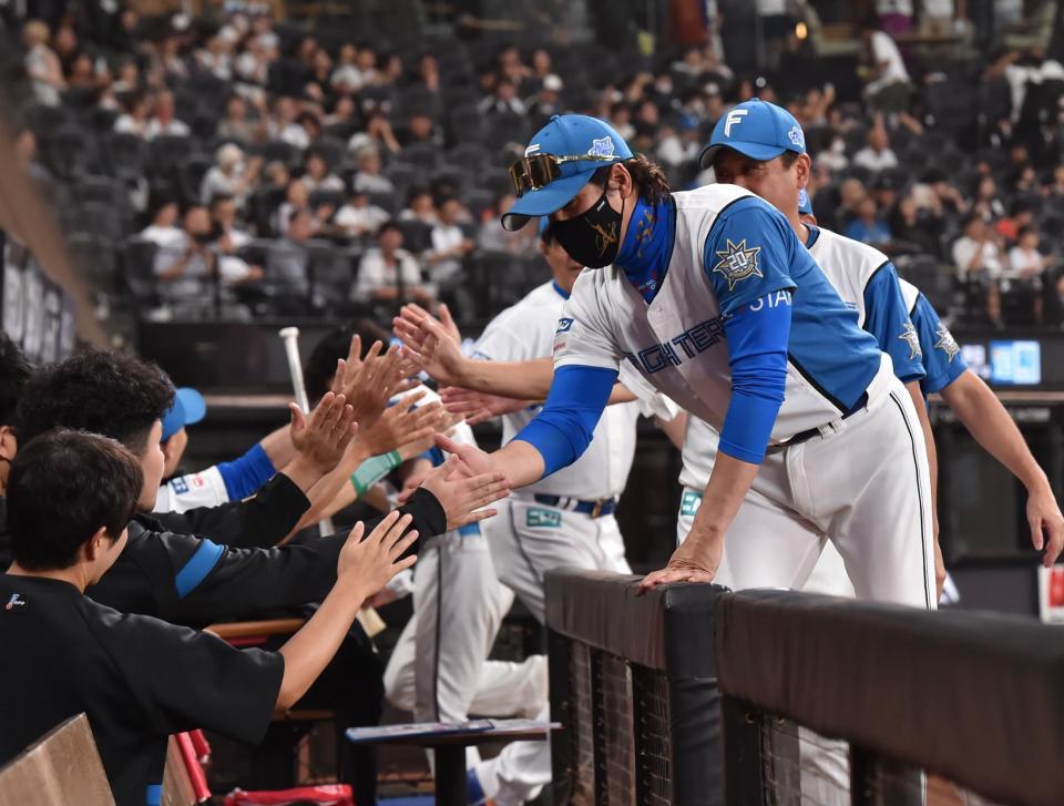 　勝利をあげ、コーチ陣とタッチを交わす新庄監督（右）＝撮影・中島達哉