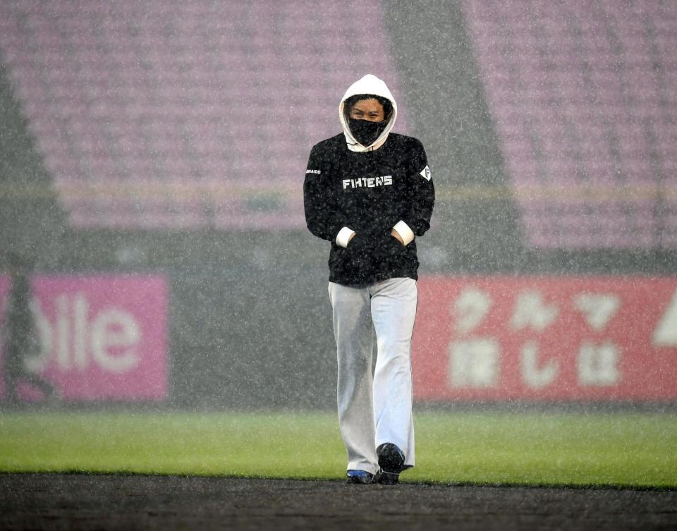 　練習中に豪雨に見舞われ苦笑いでベンチへ戻る新庄監督（撮影・棚橋慶太）