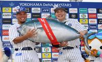 　８回途中まで力投し３勝目を挙げた浜口（左）と勝ち越し適時打を放つ活躍をみせた佐野はマグロの特大ぬいぐるみを持って笑顔（撮影・三好信也）