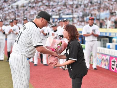 　試合後のセレモニーで吉井監督（左）から花束を受け取るアナウンス担当の谷保恵美さん（撮影・開出牧）