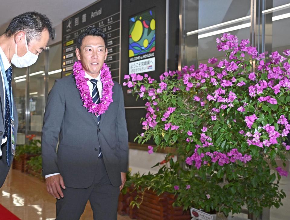 　宮崎空港に到着し、ブーゲンビリアの花の前を通る井端監督