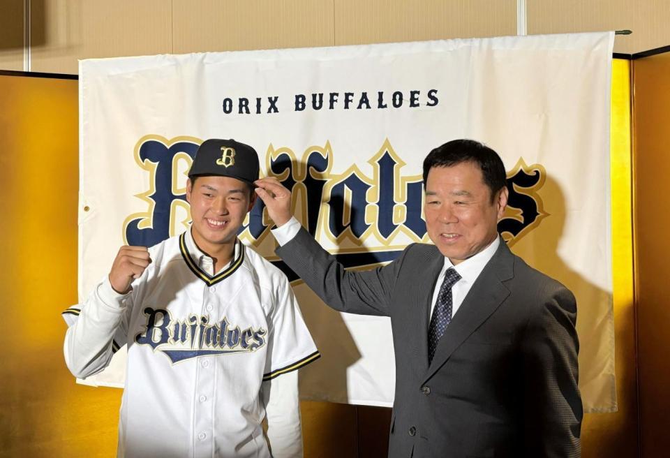 　仮契約を終え、福良ＧＭ（右）に帽子をかぶせてもらった堀