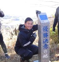 　恒例の山登りトレを行い、頂上の石碑にサインを書き込む山崎