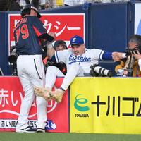 　９回、石川の飛球を捕ろうとカメラマン席に飛び込み、亀井外野守備走塁コーチ（左）に救出される一塁手の欧州代表ムジーク（撮影・伊藤笙子）