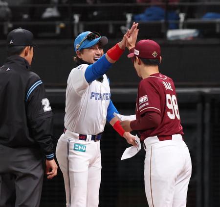 　メンバー表を交換し、今江監督（右）とハイタッチを交わす新庄監督（中央）＝撮影・中島達哉