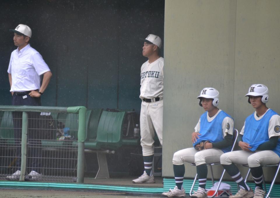 　ベンチで指揮を執る報徳学園・大角監督（右から３番目）