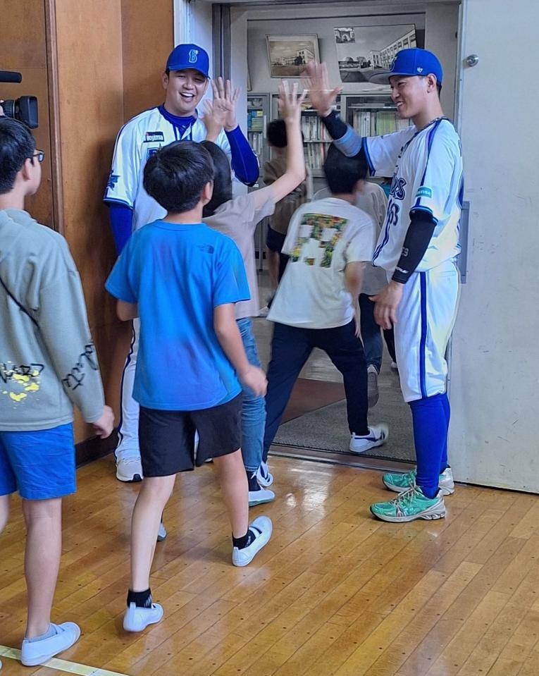 　子どもたちとハイタッチする山崎（左）と関根