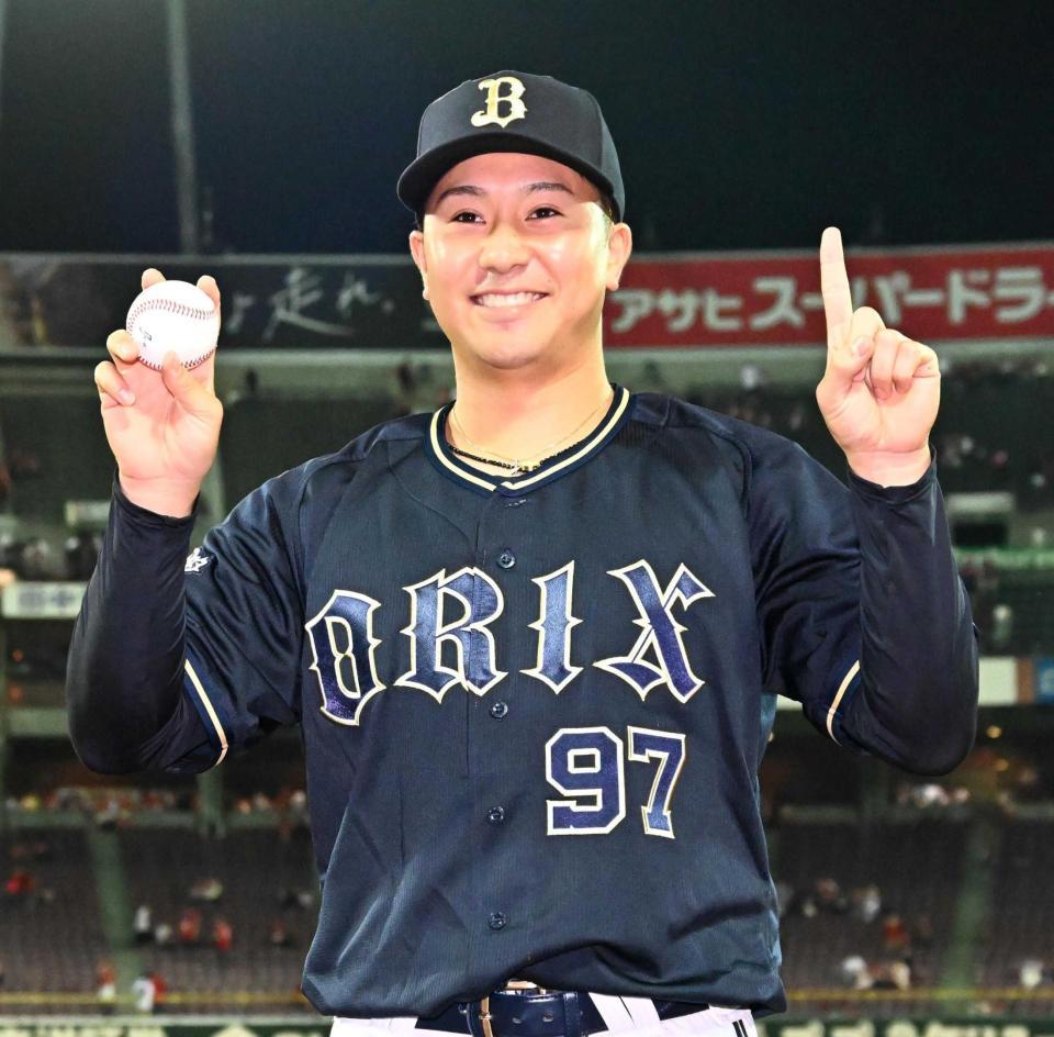 　プロ初勝利の球を手に記念撮影に応じる古田島（撮影・市尻達拡）