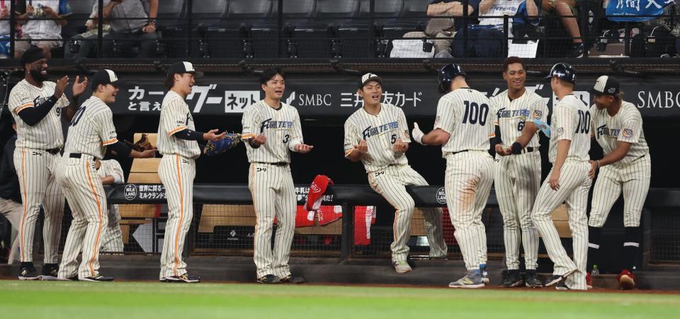 　８回、石井の適時打で生還した二走のマルティネス（右から４人目）を「ゆりかごポーズ」で迎える日本ハムナイン（撮影・中島達哉）