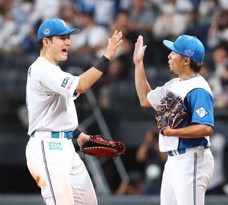 　完封勝利を挙げた伊藤（右）とタッチを交わす清宮