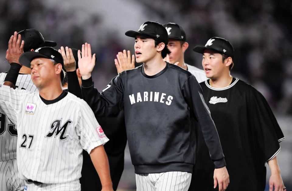 　今季８勝目を挙げナインとタッチを交わす佐々木（中央）＝撮影・開出牧