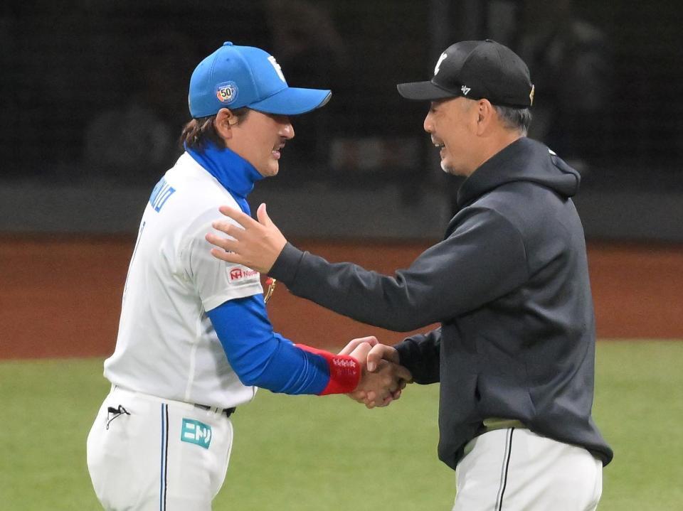 　試合後、新庄監督（左）と握手を交わし、勝利をたたえる吉井監督（撮影・伊藤笙子）