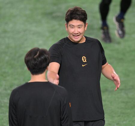 　試合前、大勢（手前）と会話を交わす菅野（撮影・伊藤笙子）