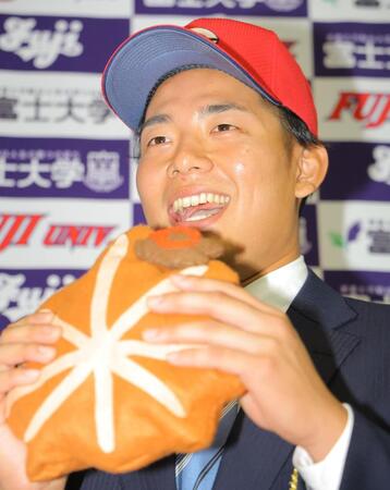 　広島４位指名を受け、もみじまんじゅうに食らい付く富士大・渡辺悠斗（撮影・吉澤敬太）