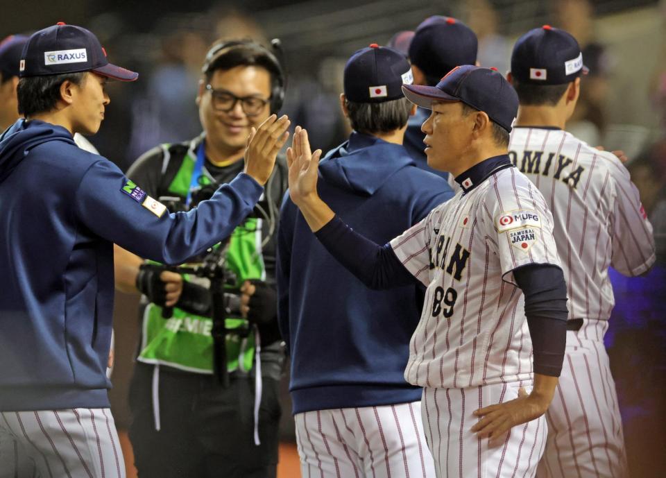 　韓国戦に勝利し、選手をハイタッチで迎える井端監督（右）