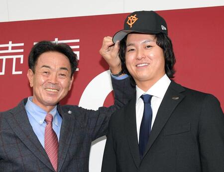 水野編成本部長代理スカウト担当兼スカウト部長（左）から帽子をかぶせてもらう田中瑛斗（撮影・佐藤厚）