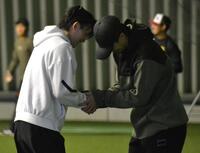 周東（左）と握手を交わす上沢