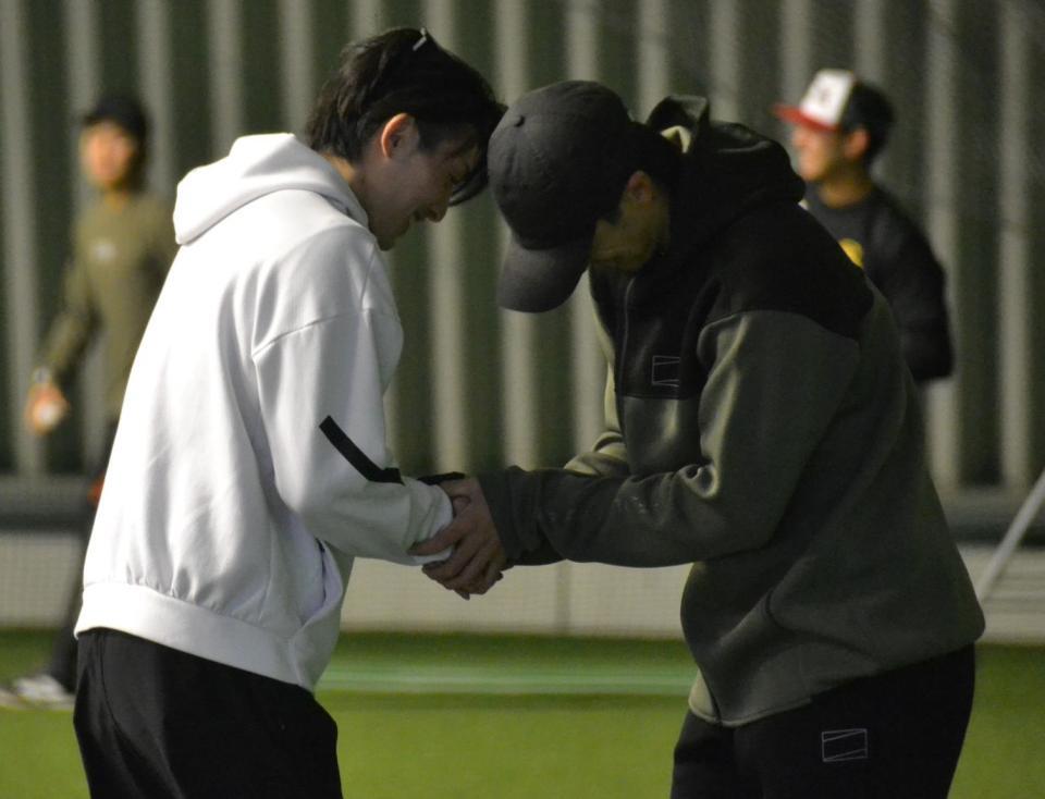 周東（左）と握手を交わす上沢
