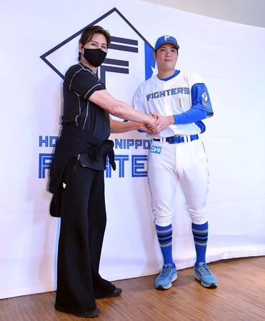 　会見で新庄監督（左）と握手を交わす古林（撮影・開出牧）