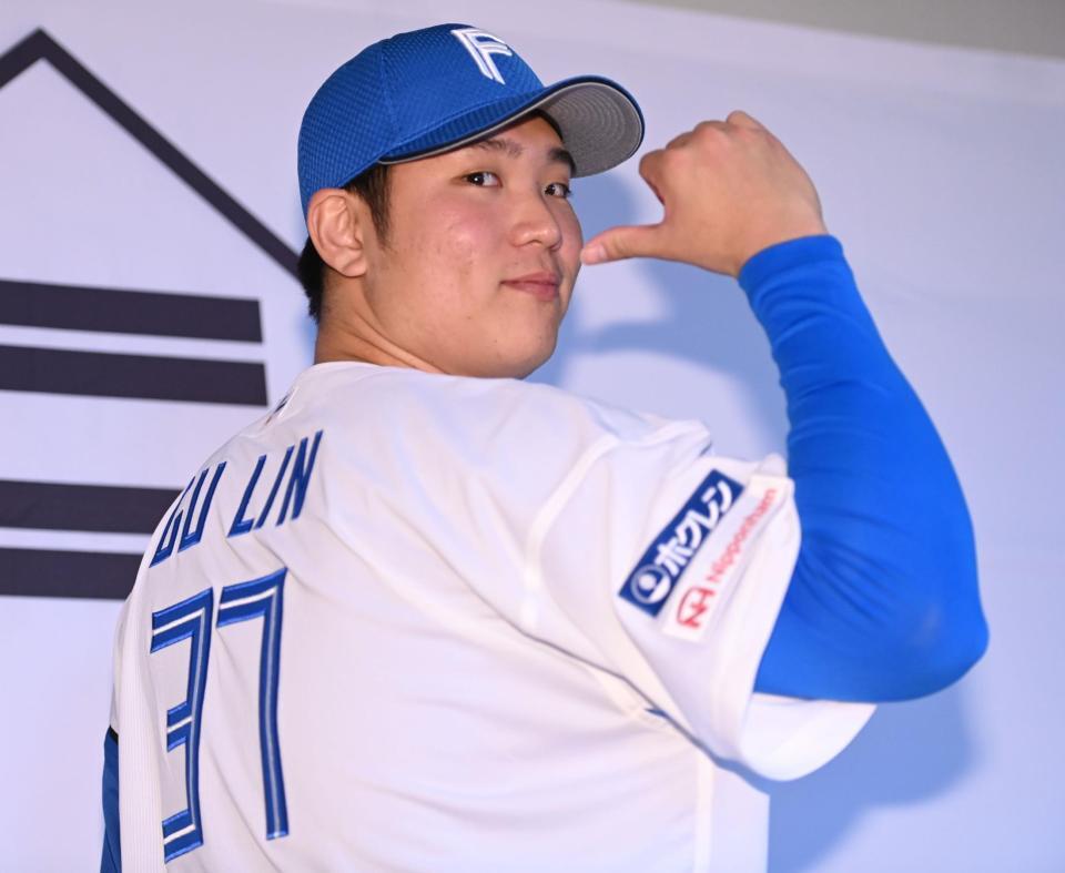 　背番号３７のユニホームに袖を通しポーズを決める古林（撮影・開出牧）