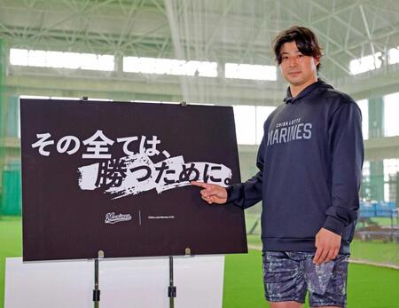 　今季のスローガンが書かれたボードを指さす藤岡