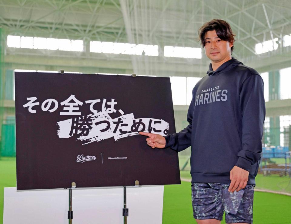 　今季のスローガンが書かれたボードを指さす藤岡