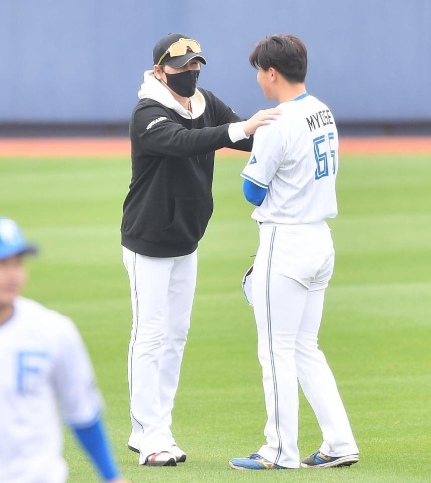 　１軍キャンプ参加の明瀬（右）の肩に手を置き激励する新庄監督（撮影・開出牧）