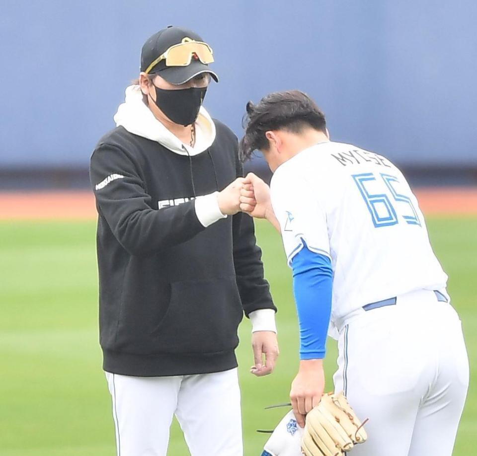 　１軍キャンプに参加の明瀬（右）をグータッチで迎える新庄監督（撮影・開出牧）