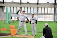 　平均台に乗りながら久保コーチ（右）とともに投球フォームを確認する田中将