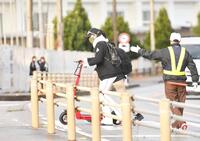 　交通マナーを厳守だ！宿泊ホテルから球場入りする途中、電動キックボードを降りて横断歩道を渡る新庄監督（撮影・開出牧）