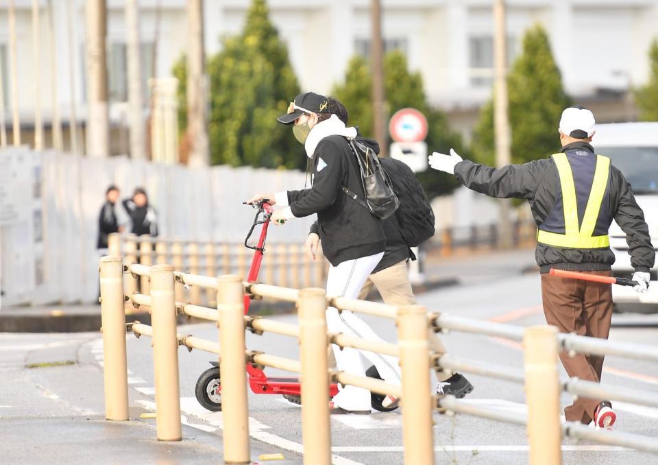 　交通マナーを厳守だ！宿泊ホテルから球場入りする途中、電動キックボードを降りて横断歩道を渡る新庄監督（撮影・開出牧）