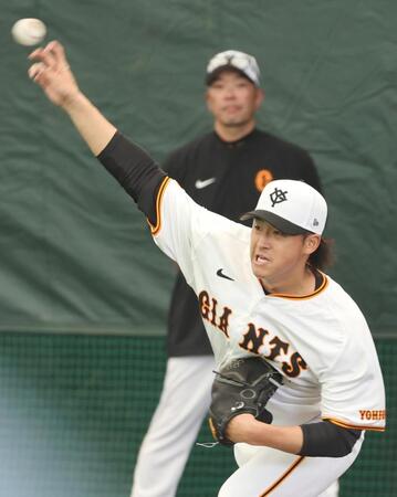 　阿部監督（後方）の視線を浴びながらブルペンで投球する巨人・堀田